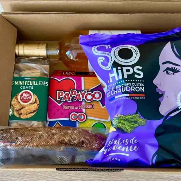 Une box ouverte : chips So Chips, le jeu Papayoo, des mini feuilletés au comté et un saucisson